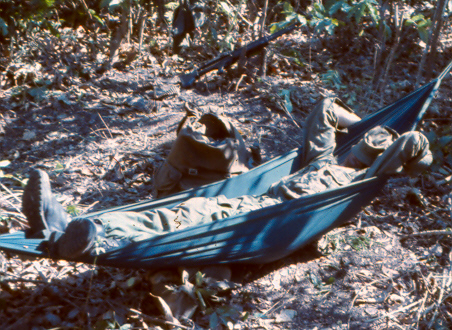 what the platoon sergeant calls 'an idle soldier...'  Hammocks in the bush were rare, M60 MG in rear not apparently manned so sentry must be forward [King]