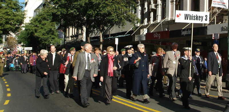 Command element of W3 Company during street parade - Upton (grey jacket), Torrance (shade on face) Fisher (right marker) & Cutler (left side in beret behind Upton [Binning]